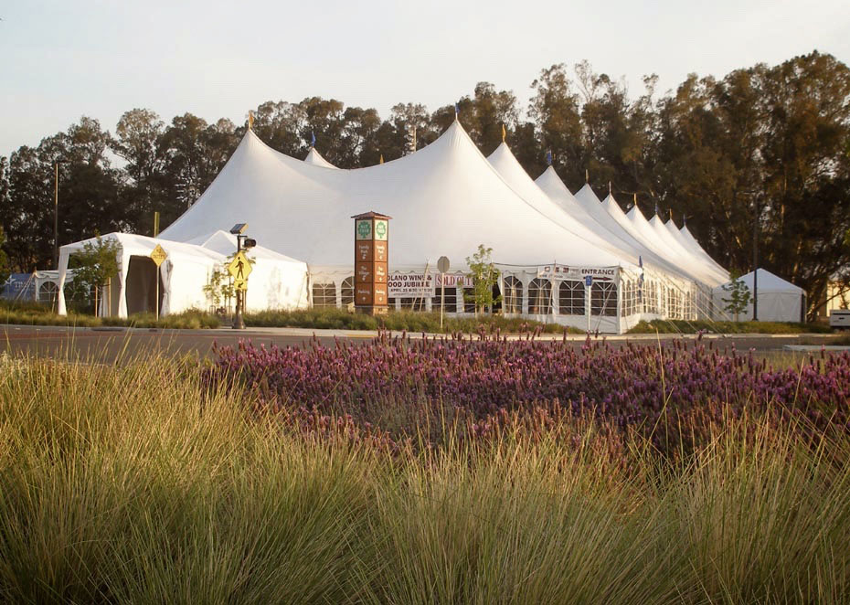 An image of large tents with some flowers and bushes nearby